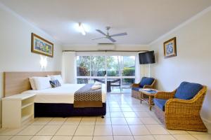凯恩斯凯恩斯昆士兰酒店公寓的一间卧室配有一张床、两把椅子和电视