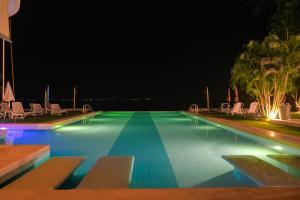 班泰神曲海滩度假酒店的游泳池,晚上配有椅子和棕榈树