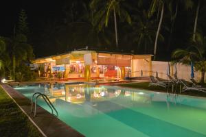 班泰神曲海滩度假酒店的一个带椅子的游泳池,晚上有房子