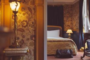 巴黎L酒店的一间卧室配有一张床和一张桌子上的台灯