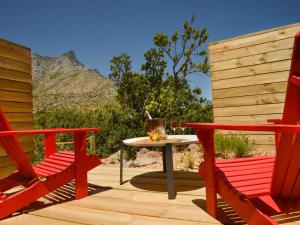 戈登湾PitStop Lodge的一个带两张红色椅子和一张桌子的庭院,并享有山景。