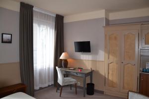 圣马洛Hotel Ajoncs d'Or的酒店客房设有书桌和窗户。