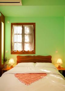 达默查理Victoria's Guesthouse的一间卧室设有一张带绿色墙壁和窗户的床。