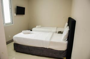 马普托Residencial Horizonte 2的小客房内的两张床,配有白色床单