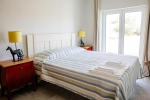 马尔旺Casas da Estação的一间卧室配有一张带条纹毯子的床和窗户