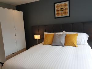 卡迪夫The Spires Serviced Apartments Cardiff的卧室配有一张带黄色枕头的大型白色床。