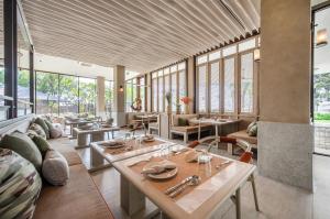 七岩VALA Hua Hin - Nu Chapter Hotels的餐厅设有桌椅和窗户。