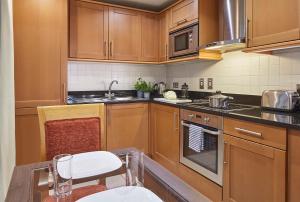 伦敦Marlin Apartments London City - Queen Street的厨房配有木制橱柜和桌椅