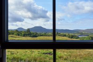 邓韦根Dunvegan Castle The Farmhouse Cottage的从田野和山脉的窗户欣赏美景