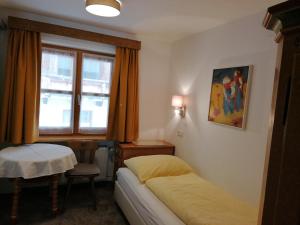 圣安东阿尔贝格Landhaus Sonnenberg的一间卧室配有一张床、一张桌子和一个窗户。