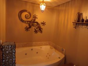 格拉玛多Shanti Ghar - Apto junto ao Centro de Gramado的浴室配有浴缸,墙上挂着蜥 ⁇ 