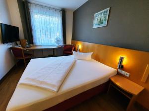 灵斯海姆Hotel SunParc - SHUTTLE zum Europa-Park Rust 4km & Rulantica 2km的卧室配有一张白色大床和一张书桌