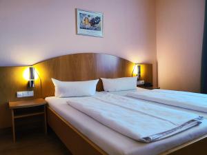 灵斯海姆Hotel SunParc - SHUTTLE zum Europa-Park Rust 4km & Rulantica 2km的一张位于酒店客房的床铺,配有两张白色的床