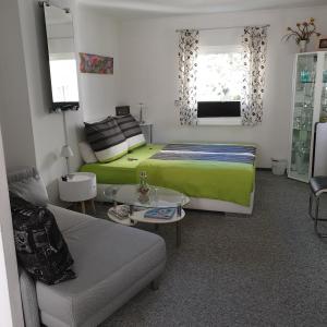EichwaldeFerienapartment MOHNBLUME的一间卧室配有绿色的床和沙发