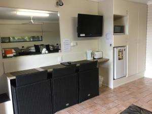 班达伯格黄金棕榈汽车旅馆的厨房配有黑色橱柜和墙上的电视。