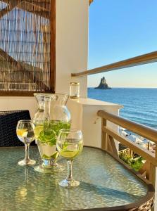 阿齐欧斯·贡多斯Nereides Apartments的坐在桌子上,一边欣赏大海,一边喝三杯葡萄酒