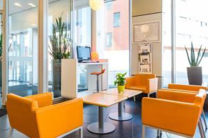 鲁汶埃塔鲁汶中心酒店的办公室配有橙色椅子、桌子和书桌