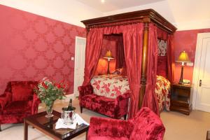 埃尔金广厦酒店的红色卧室配有床和桌椅
