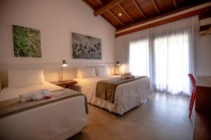 皮帕Pousada Alto da Pipa的酒店客房设有两张床和窗户。