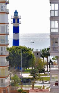 托雷德尔马尔Magnifico ático en la playa的蓝色和白色的灯塔,在海洋前
