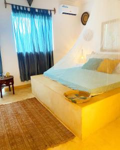 ChanjaniFURAHA VILLA 3的一间卧室配有一张带蓝色窗帘的大床