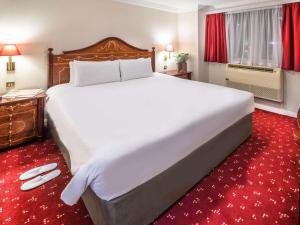 伦敦伦敦伯爵府宜必思酒店的一张大白色的床,位于酒店客房,铺有红地毯