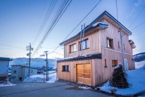 野沢Tamanegi House luxury 4 bedroom Ski Chalet的木屋,雪中设有木门