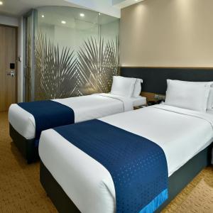 新加坡Holiday Inn Express Singapore Orchard Road, an IHG Hotel的两张睡床彼此相邻,位于一个房间里