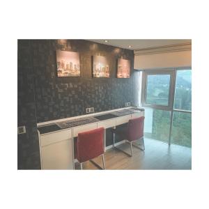 峇六拜The ceo suites by Zenbnb的厨房配有柜台和2把红色椅子