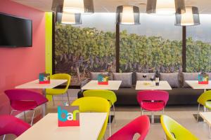 雅莱地区圣梅达尔波尔多圣梅达尔达宜必思尚品酒店的用餐室配有五颜六色的桌椅和壁画