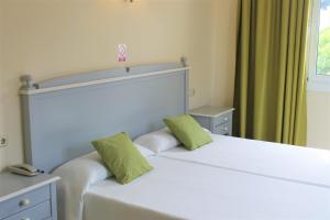埃尔阿雷纳尔索尔海滩酒店的一间卧室配有两张白色床和绿色枕头