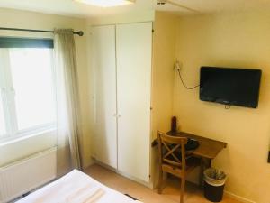 维辛瑟Wisingsö Hotell的卧室设有壁挂式电视和椅子