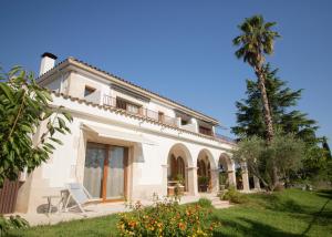 赫罗纳Villa Montjuic Girona的院子里有棕榈树的白色房子
