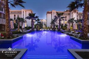 阳光海滩Cascadas Family Resort的一座大型游泳池,在一座建筑前种有棕榈树