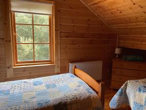 百利科内尔Riverside log cabin的一间位于小屋内的卧室,配有一张床和一个窗户