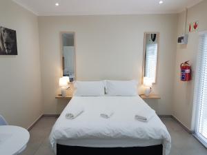 开普敦Sharon's House: Modern Self-Catering rooms的一间卧室配有一张带两盏灯的大型白色床。