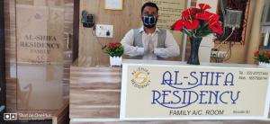 孟买AL Shifa Residency的戴着防毒面具的男子站在标志后面
