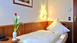 科隆依贝茨嘉利酒店的一间酒店客房,配有一张床和一个花瓶