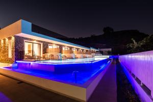 法里拉基Zoes Hotel & Suites的游泳池在晚上点亮,紫色灯