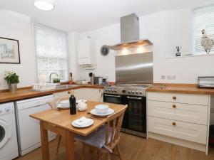 巴克斯顿2B Cavendish Villas的一间带木桌的厨房和一间带白色橱柜的厨房