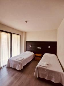 萨拉戈萨Hotel Delicias的客房设有两张床和大窗户。