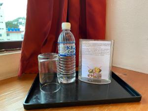 哥打京那巴鲁得利通酒店的塑料托盘,装有一瓶水和玻璃