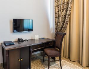 塔尔迪库尔干Royal Petrol Hotel的一张桌子、椅子和墙上的电视