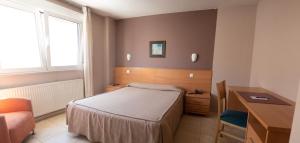 卢戈卢戈城市公寓酒店的小房间设有一张床、一张桌子和一张书桌