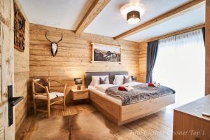 洛伊塔施Chalet Leßner的卧室设有木墙、一张床和椅子