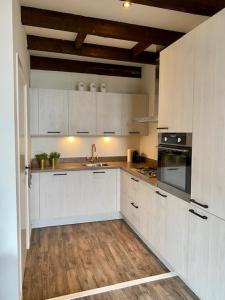 米德尔堡Torenkamer Middelburgh的厨房铺有木地板,配有白色橱柜。