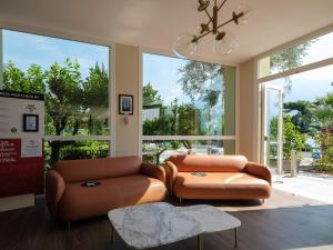 利莫内-苏尔加达莱昂纳多·达·芬奇酒店的客厅设有2个棕色皮革座椅和窗户