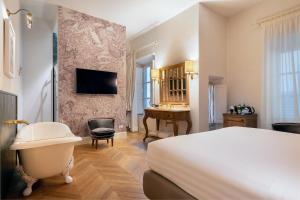 佛罗伦萨Corte Calzaiuoli Elegant Suites的酒店客房配有一张床、一个浴缸和一张书桌。