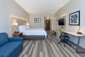 大急流城Holiday Inn Express & Suites - Grand Rapids Airport - South, an IHG Hotel的酒店客房配有一张床、一张书桌和一张沙发。