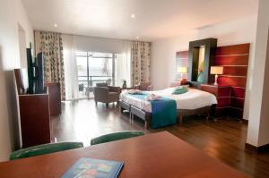 克拉伦代克Van der Valk Plaza Beach & Dive Resort Bonaire的酒店客房带一张床、一张桌子和椅子